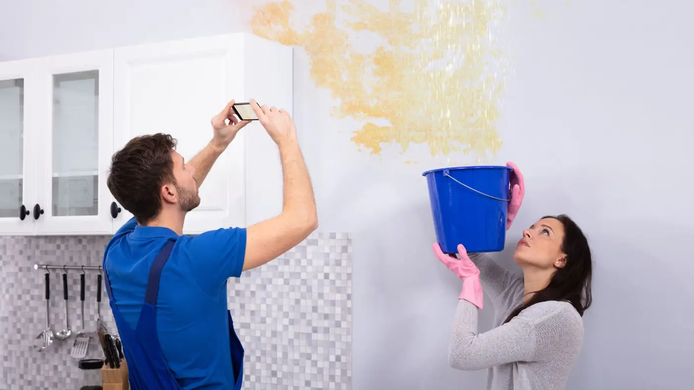 Homeowner photographing a water stain on a wall for an insurance claim