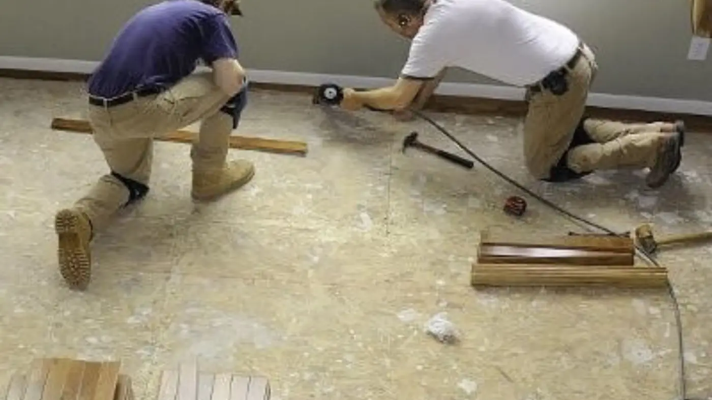 Two workers installing new flooring during a water damage repair